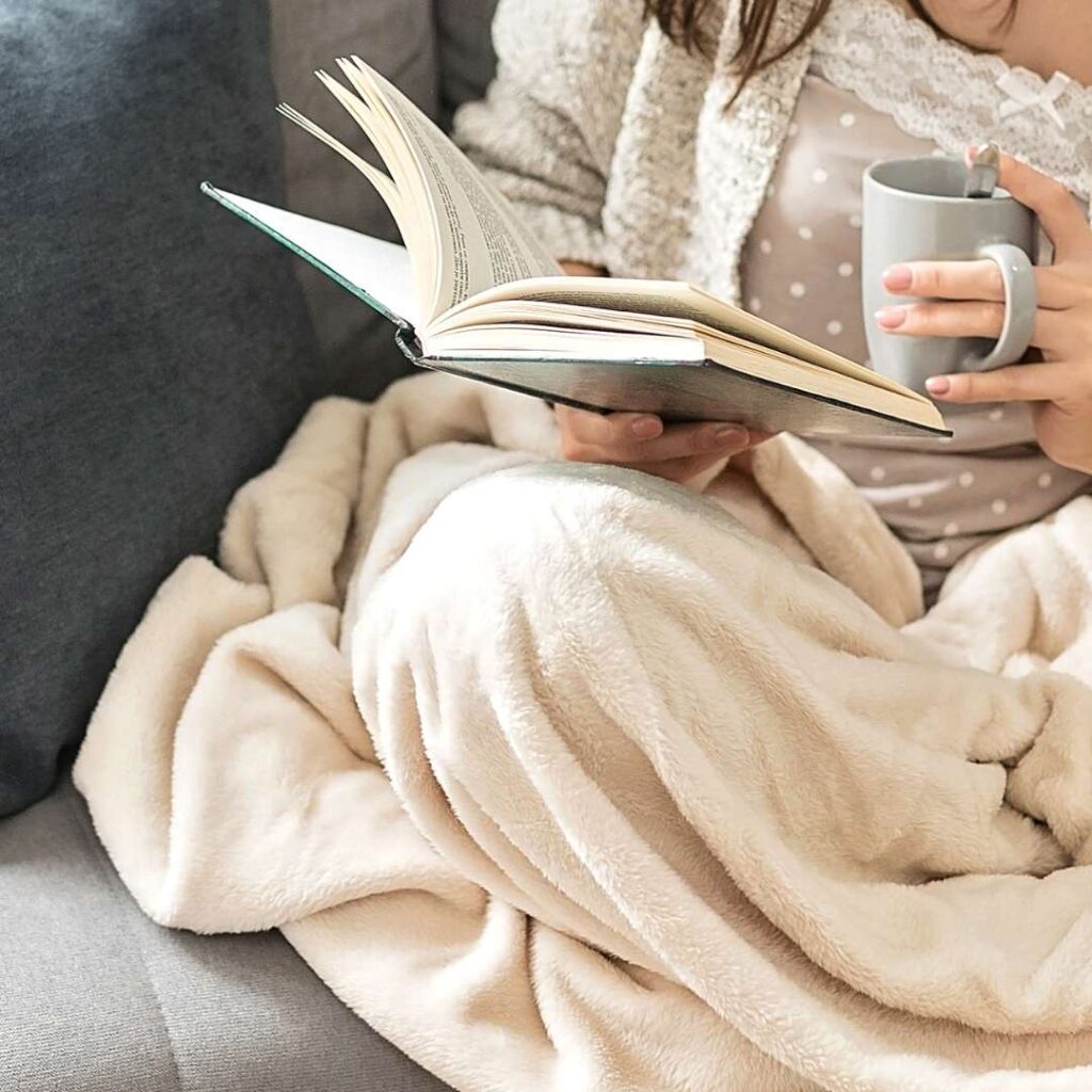 Woman reading a book and holding a grey mug